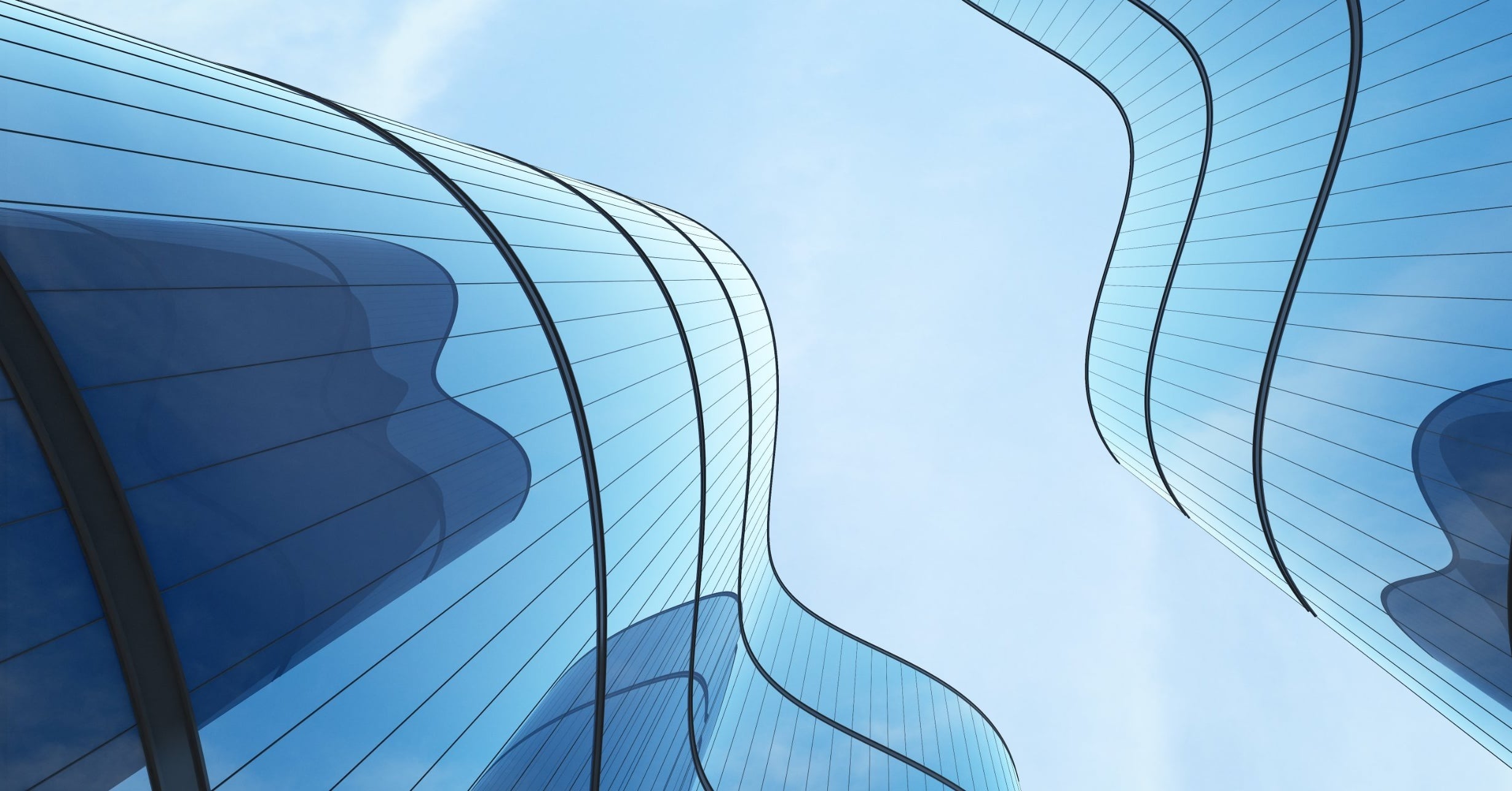 Looking up at curved glass skyscrapers with flowing, wave-like facades against a pale blue sky.